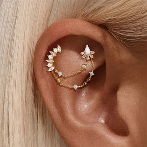 Macro shot of gold ear cuff with opal stones, zircons and delicate star chain tassels