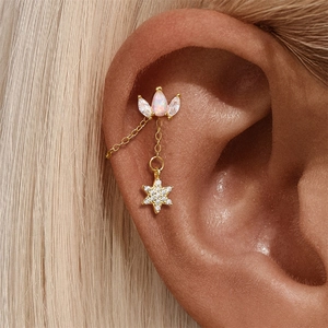 Detail of gold star chain earring with opal and zirconia in a stylish layered design