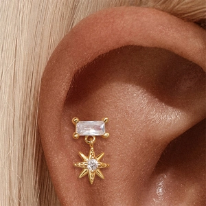 Detailaufnahme eines goldenen Sternanhängers mit Zirkon-Ohrring am Ohrmodell