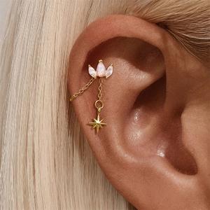 Close-up of gold star earrings with pink opal and zircon on a long chain dangle