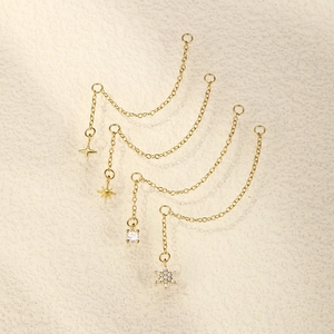Macro detail of gold star and heart drop earrings with delicate chains and cubic zirconia