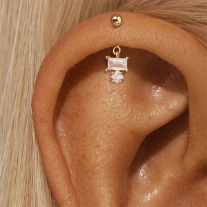 Detail van vergulde s925 zilveren oorpiercing met zirkonia stenen op menselijk oor