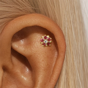 Vue macro d'un piercing fleur en argent 925 avec pierres roses sur l'oreille