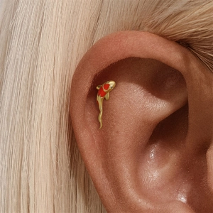 Vue macro d'un piercing cartilage carpe koï doré avec émail rouge et strass