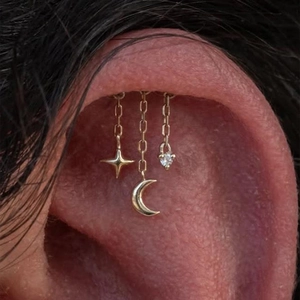 Gros plan d'une boucle d'oreille S925 argent avec lune, étoile et chaîne sur l'hélix