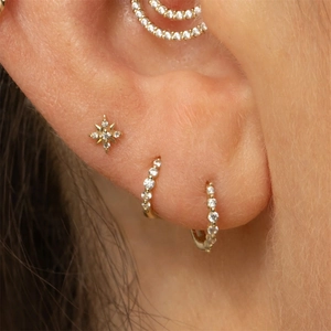 Vue macro des boucles d'oreilles dorées à pampilles avec zircon en étoile sur cartilage