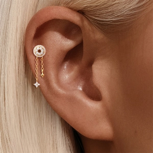 Detail van S925 zilveren piercing met bloem gouden kwastje en kleine ster hanger