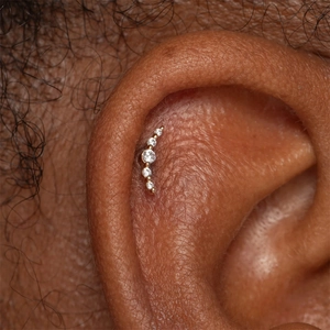 Vue macro d'un clou d'oreille en argent S925 avec cinq zircons brillants sertis d'or