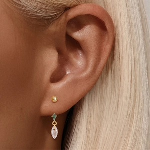 Macro detail of gold ball stud and drop earring with green stone and clear zircon
