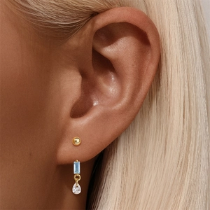 Close-up of S925 silver gold-plated stud set with blue gemstone and pear-shaped crystal