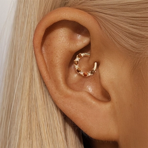 Close-up of golden helix hoop earring featuring alternating tiger eye and zircon stones