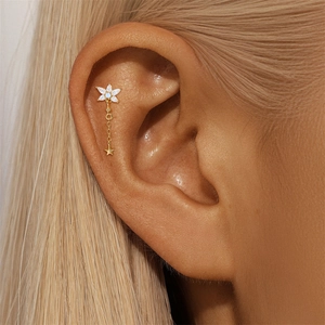 Detailed shot of gold plated silver earring with star tassel and zircon flower