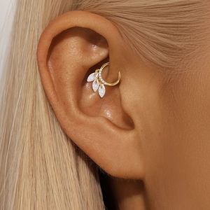 Close-up of gold ear piercing with marquise cut opal stones and diamonds on cartilage