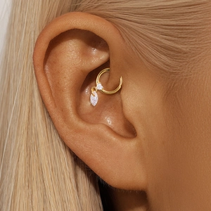 Macro shot of gold daith piercing ring featuring two marquise-cut zircon stones on ear
