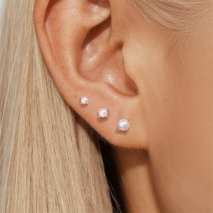 Vue macro de trois boucles d'oreilles en perles S925 de tailles graduées sur un mannequin