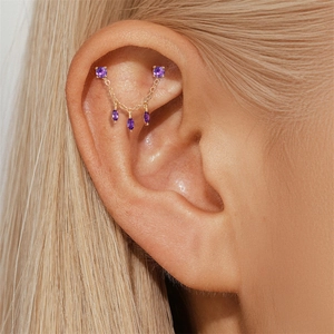 Close-up of gold chain earring with purple amethyst stones worn on the ear cartilage