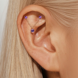 Macro shot of gold-plated triple purple amethyst zircon cartilage chain earring on ear