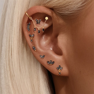 Macro detail of S925 silver ear piercing set featuring black gemstones and floral designs