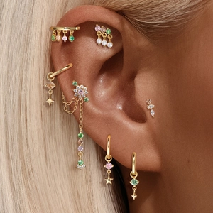Detailed close-up of gold S925 silver cartilage studs with colorful zircons and stars