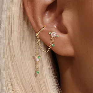 Makroansicht von goldenem Earcuff mit rosa Blumenstecker und Zirkonanhängern am Ohr