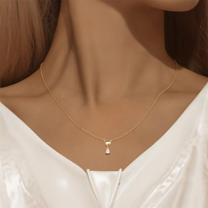 Detail der goldenen Herz- und Tropfenkristallkette auf minimalistischem Silber
