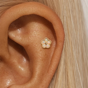 Macro shot of 925 silver flower stud earring with opal inlay worn on ear cartilage