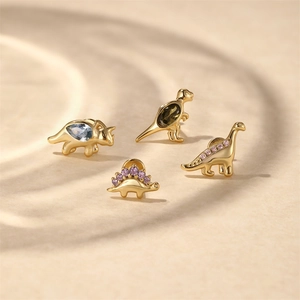 Detailed close-up of S925 silver dinosaur studs with colorful zircon on sandy background