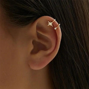 Macro primo piano di un ear cuff a doppio strato a stella dorata con zirconi sull'orecchio