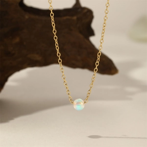 Detailansicht einer minimalistischen Goldkette mit einem schillernden Opal-Perlenanhänger