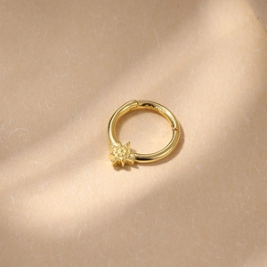 Macro detail of gold-plated S925 silver hoop earring with a small starburst charm