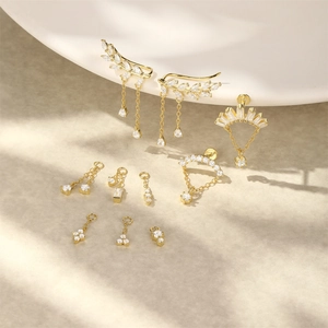 Makroaufnahme von vergoldeten Blatt-Quasten-Ear-Cuffs und geometrischen Zirkonia-Anhängern