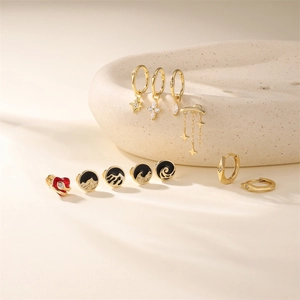 Détail de boucles d'oreilles en argent doré avec motifs étoile, croix et émail en relief