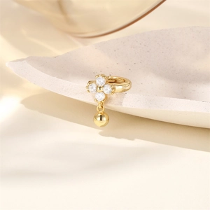 Detailed close-up of a gold star-shaped silver hoop earring with polished metal ball drop