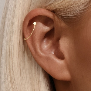 Primer plano de pendiente de plata S925 dorada con cadena box y ear cuff moderno