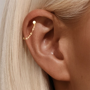 Detail of a minimalist gold link chain earring with cartilage cuff on woman ear