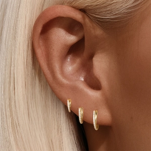 Detail of stacked gold 925 silver hoop earrings with pavé crystals on the ear