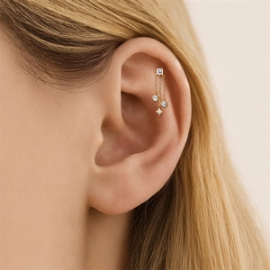 Vista macro di un earcuff dorato con pendente a stella e catena con cristalli