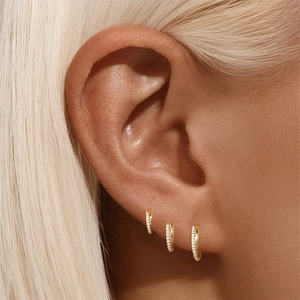 Close-up of three gold pavé hoop earrings worn on ear with sparkling cubic zirconia stones