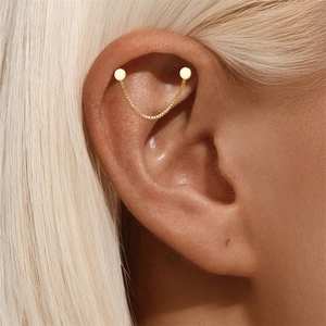 Detalle de un ear cuff de plata S925 dorada con doble pendiente y cadena fina brillante
