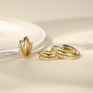 Close-up of triple-layered gold hoop earrings with zircon pavé setting and polished finish