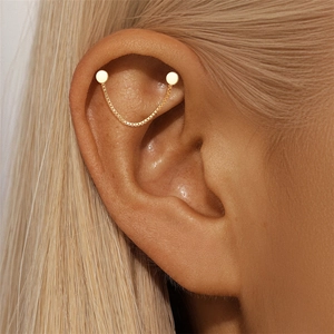 Detail of gold box chain earring featuring dual round stud connectors on ear