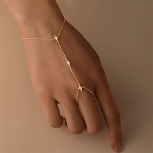 Détail macro de la chaîne de main dorée avec zircon blanc taille marquise sur la main