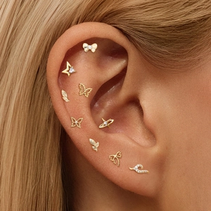 Detailed view of nine gold S925 silver bowknot and butterfly stud earrings on ear