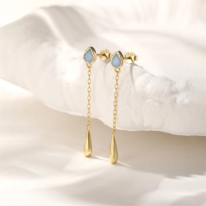 Macro shot of S925 hallmark on gold drop earrings with blue opal and sleek tassels