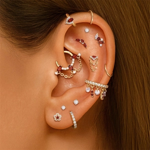 Detailed close-up of S925 silver ear studs with red garnets and gold chain tassels