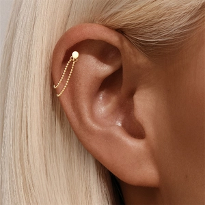 Macro shot of gold-plated silver ball chain earring on cartilage with a minimalist design