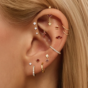 Detail of S925 silver ear piercing set with red garnets and gold-plated star designs