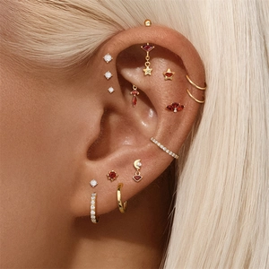 Close-up of gold s925 silver ear piercing set with red garnets and stars for women