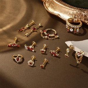 Retro gold ear piercing set with red garnet and white zircon on vintage fabric background