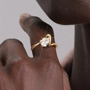 Nahaufnahme eines goldenen Wellenrings mit ovalem Zirkon an der Hand eines Models